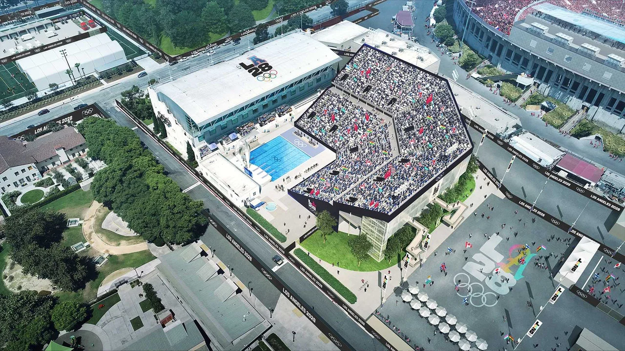 Rendering of the 1932 Pool in Exposition Park, also known as the John C. Argue Pool, set up for the Los Angeles 2028 Olympic Games. The pool is surrounded by crowded seating areas with spectators waving international flags. The area around the pool features Olympic-themed signage, including "Los Angeles 2028" banners and logos. Nearby are other sports facilities and green spaces.