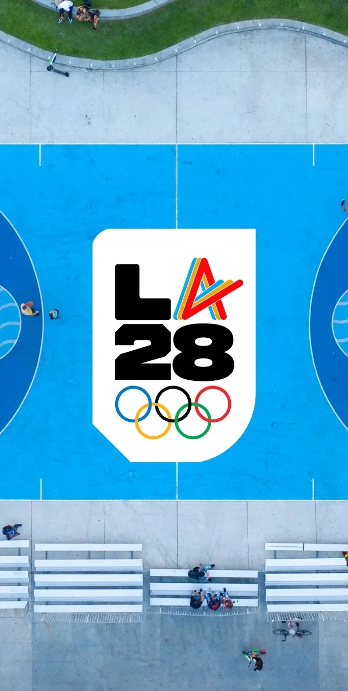 LA28 Olympic Athlete Spirit A emblem overlayed over the background of an outdoor sports court with blue flooring