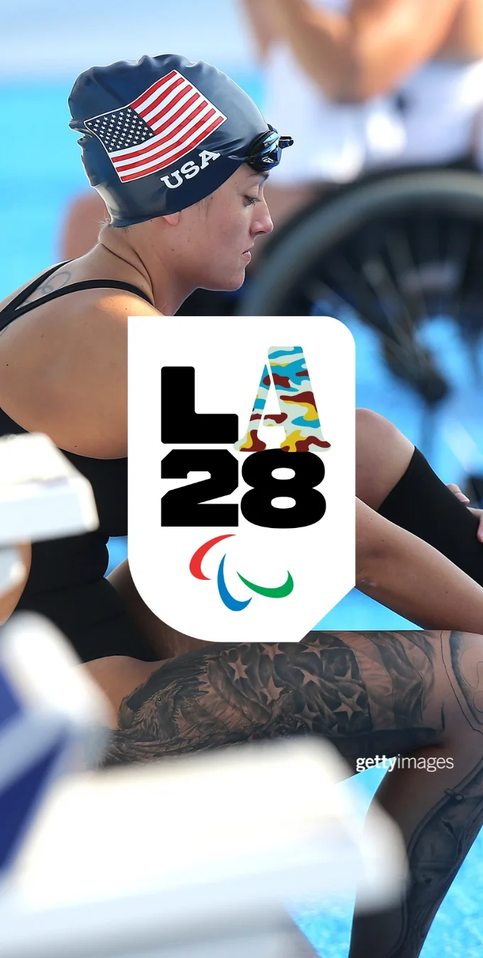 Fotografía de la nadadora paralímpica Elizabeth Marks sentada junto a una piscina, en bañador, con un gorro de natación del Team USA y colocándose la prótesis de pierna. El emblema de la 'A' paralímpica de Camuflaje de LA28 aparece superpuesto sobre la fotografía.